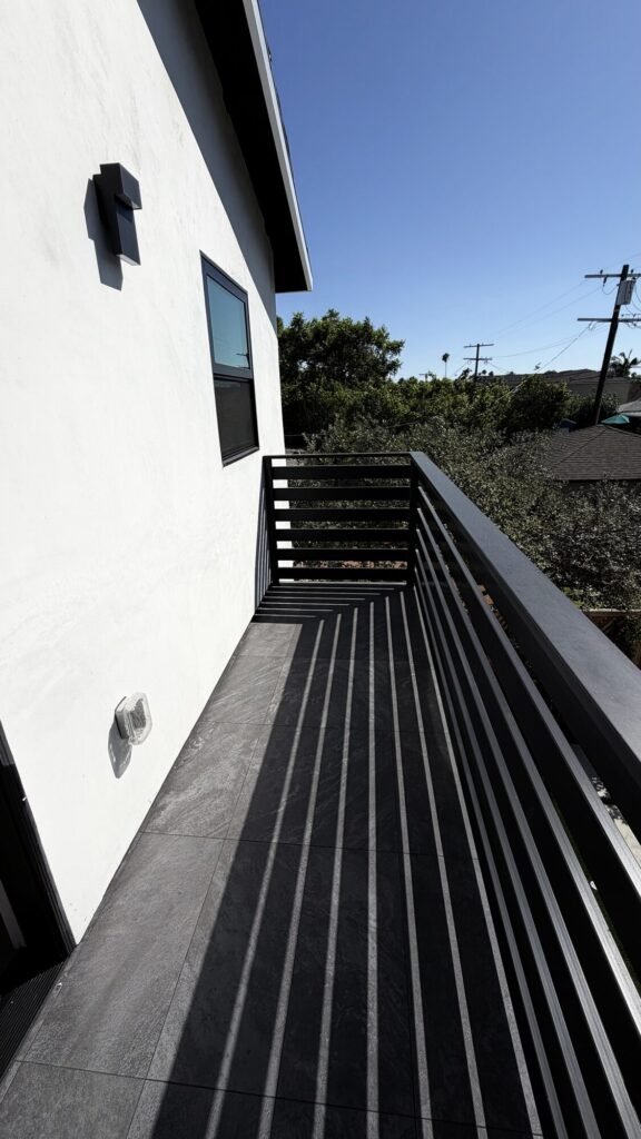 New balcony with black metal railing on a stucco exterior - Rafa Home Builders