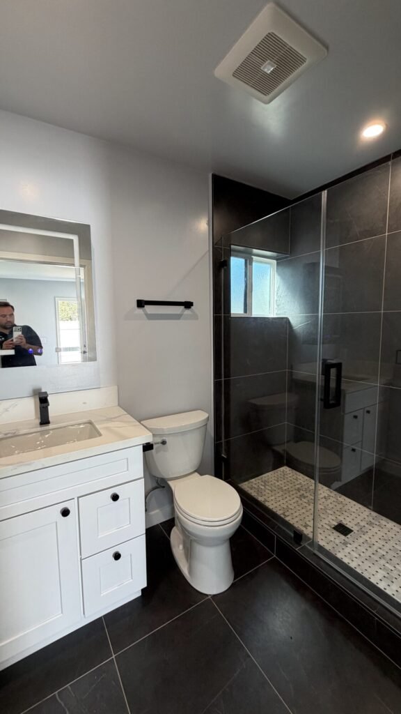 Bathroom remodel with glass shower, matte black fixtures and white vanity - Rafa Home Builders