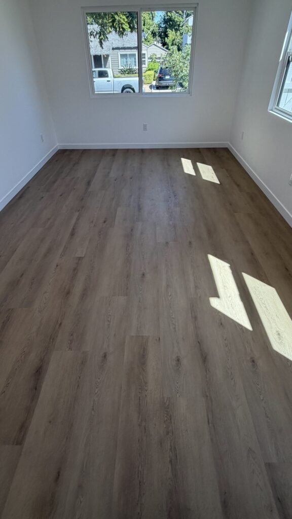 Freshly remodeled room with new vinyl plank flooring and white walls - Rafa Home Builders