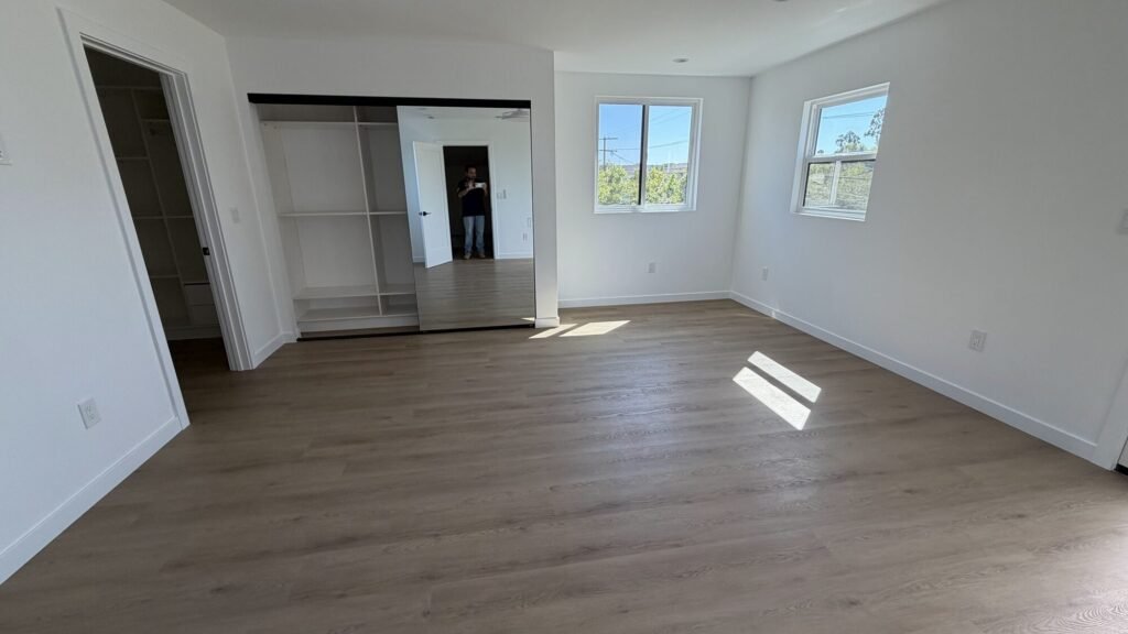 Remodeled bedroom with new flooring, closet and large windows - Rafa Home Builders