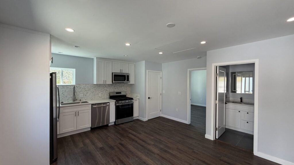 Open-concept kitchen and living area with new vinyl plank flooring and recessed lighting - Rafa Home Builders